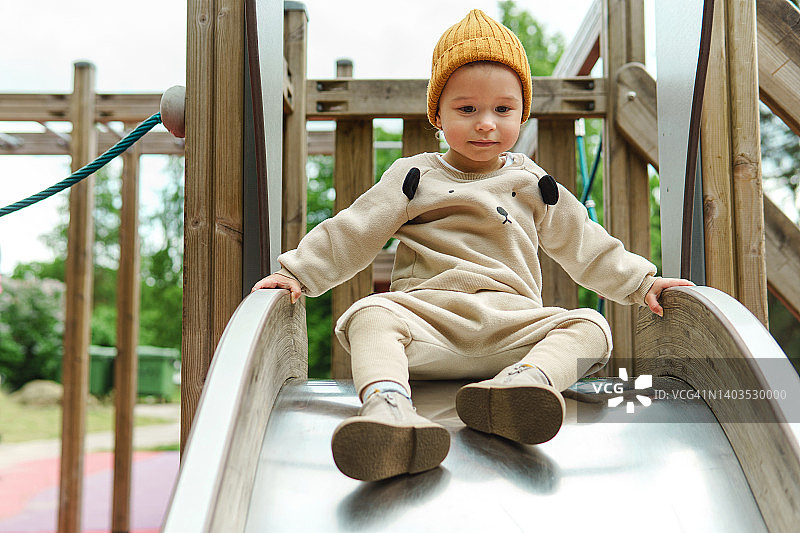 可爱的小男孩坐在公园里的滑梯上图片素材