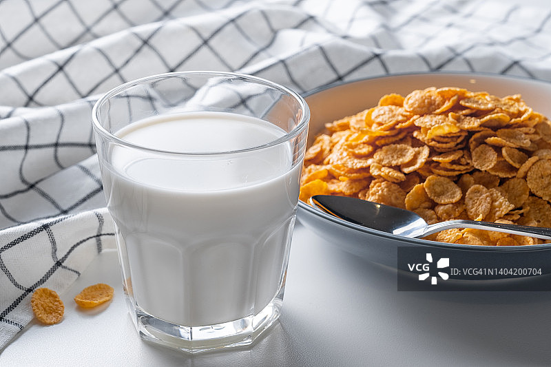 把蜂蜜干玉米片放在家里餐桌上的陶瓷盘子里，或者放在白色背景上。一杯有机农场蔬菜大豆，杏仁或动物奶。俯视图，复制空间。健康饮食的理念，素食和纯素的早餐。图片素材