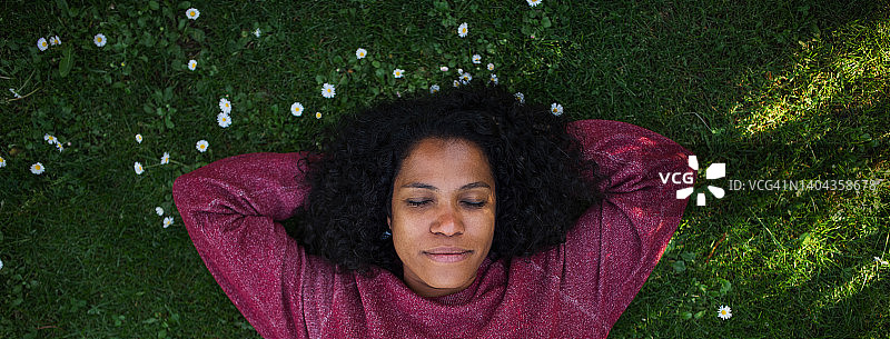 多种族妇女躺在草地上享受夏日时光的肖像。图片素材