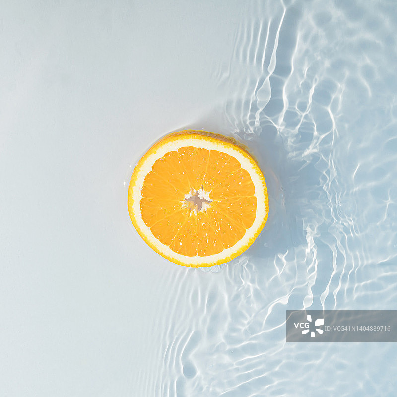 一片浸泡在水中的橙子。最小平铺概念。水果，夏日清爽灵感。图片素材