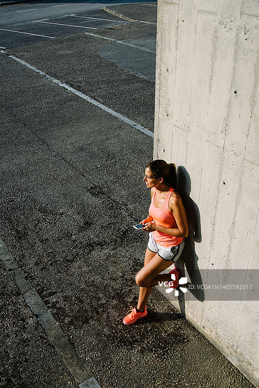 运动女性在城市锻炼休息期间用智能手机发短信图片素材