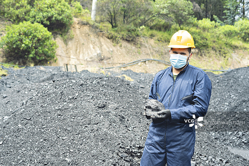 一名矿工在矿井中捧着一块煤的肖像。图片素材
