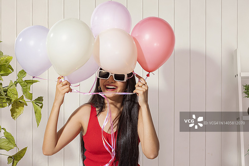 欢快的年轻女子手持彩色气球的肖像图片素材