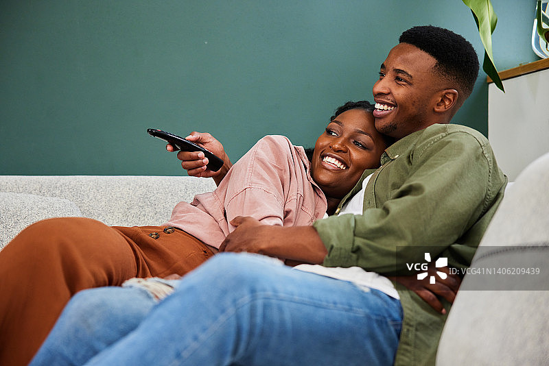 微笑的年轻夫妇坐在沙发上看电视图片素材