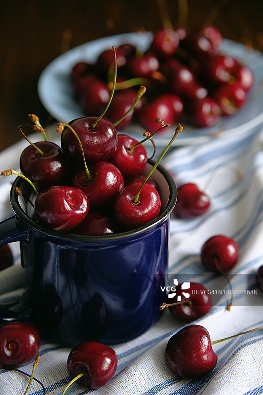 红熟甜樱桃装在马克杯里，放在餐厅或厨房的桌子上。素食，纯素和生食食品和饮食。素食主义的概念，纯素食主义和生食。蔬菜食品。从农场到餐桌。道德消费。图片素材