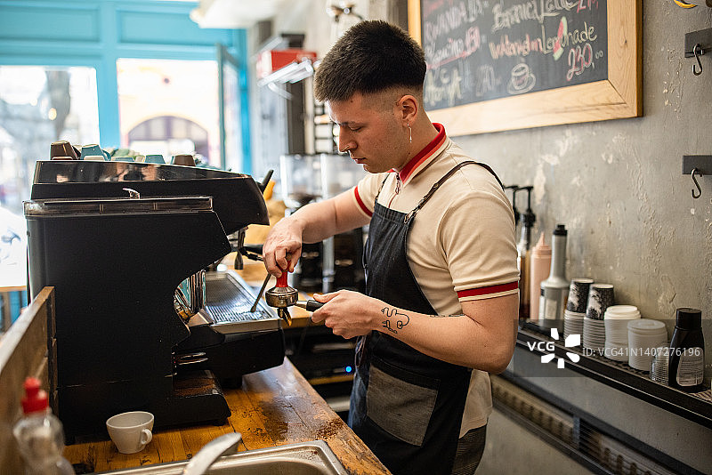 咖啡店的咖啡师一边用咖啡机一边煮咖啡图片素材