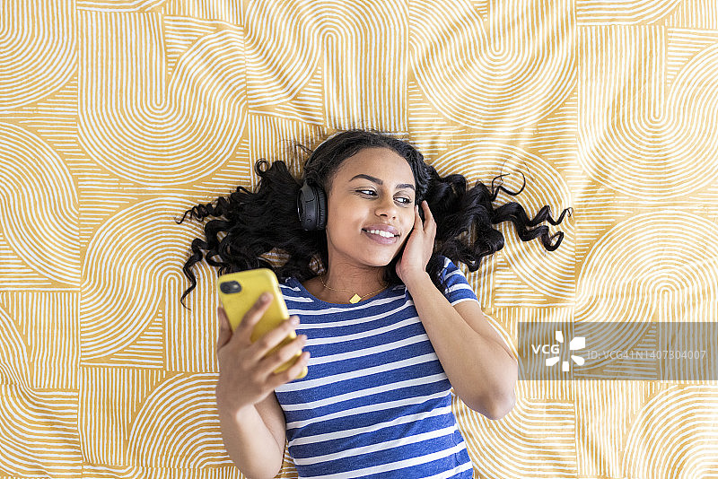 年轻女子在卧室用智能手机听音乐图片素材