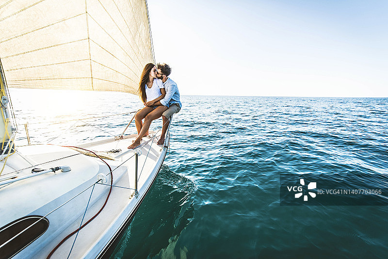 年轻情侣在游艇上放松-一对情侣在海上的帆船上享受暑假体验-夏日假期和豪华旅行的概念图片素材
