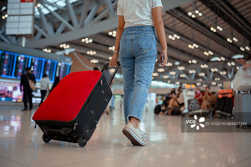 机场概念中的旅行箱旅行者。年轻的女孩带着行李步行，旅客为旅游旅行订机票，在国际假期的假期休息和放松。图片素材