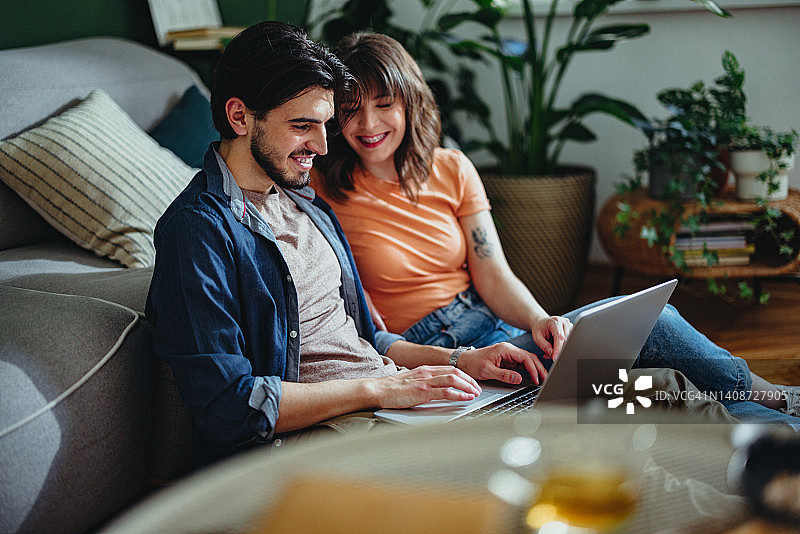 微笑的夫妇在家里一起使用笔记本电脑图片素材