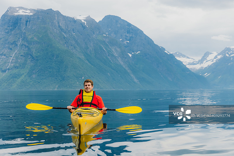 快乐的男人旅行者享受夏天在挪威风景优美的峡湾皮划艇图片素材