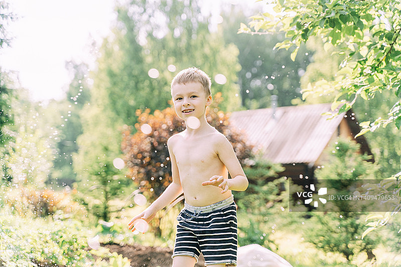 小男孩在后院玩洒水车。图片素材