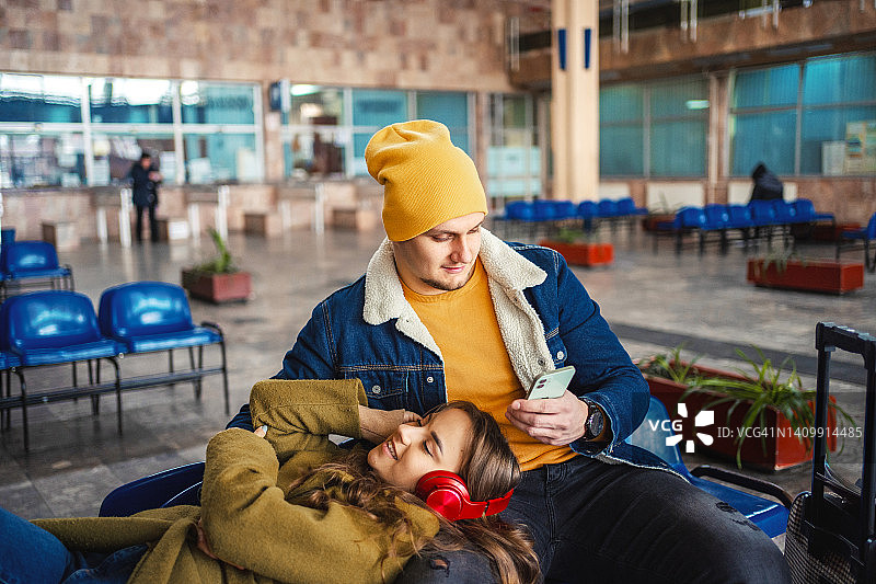 一对年轻夫妇在火车站候车时休息图片素材