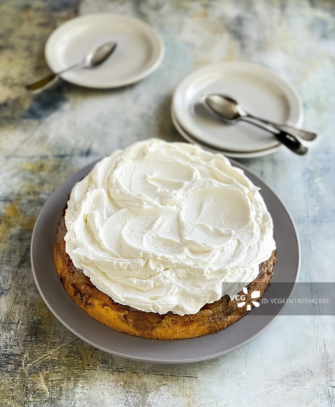 整块蛋糕和鲜奶油放在一个盘子里，在五颜六色的风化背景上图片素材