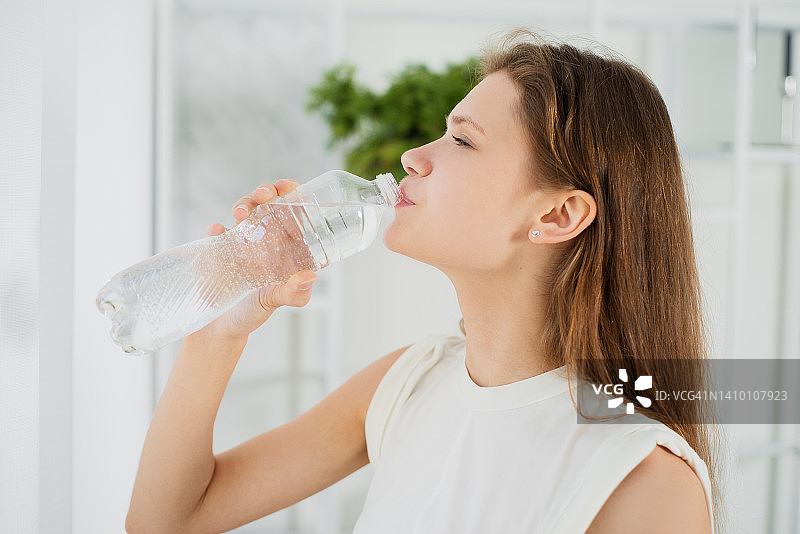 运动的年轻女子用塑料瓶喝水图片素材