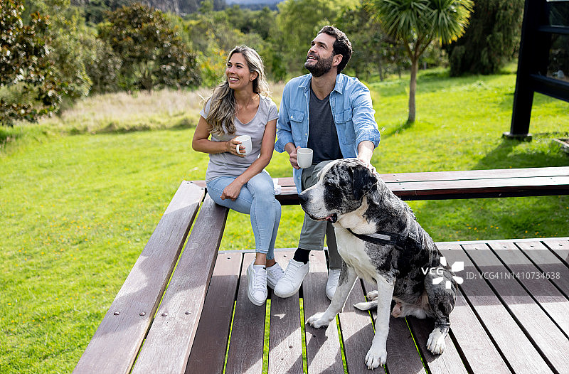 幸福的夫妇和他们的狗狗在屋外喝咖啡图片素材