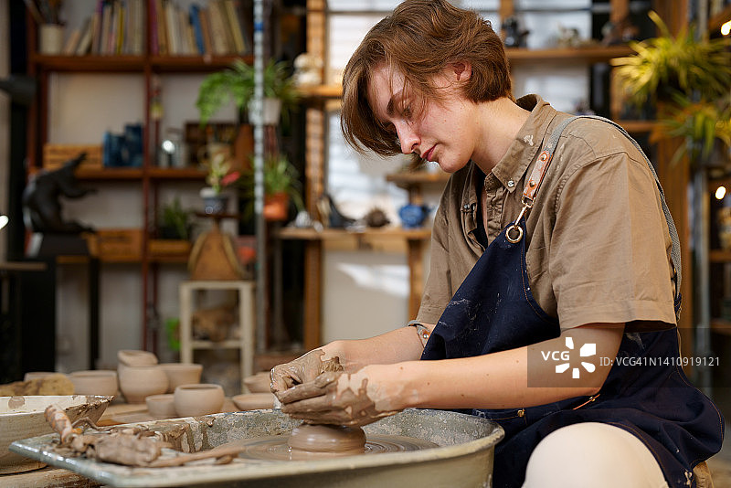 陶瓷艺术家女人塑造粘土在陶器车轮在工作室工作场所图片素材