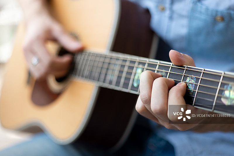 男人的手演奏原声吉他的特写。乐器娱乐或爱好激情的概念。图片素材