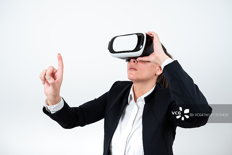 一名女子戴着虚拟现实眼镜，用一根手指指向重要信息。女商人戴上虚拟现实眼镜，展示重要信息。图片素材