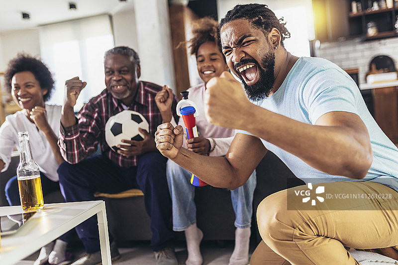 快乐的几代人家庭在家里的客厅看电视上的足球比赛图片素材