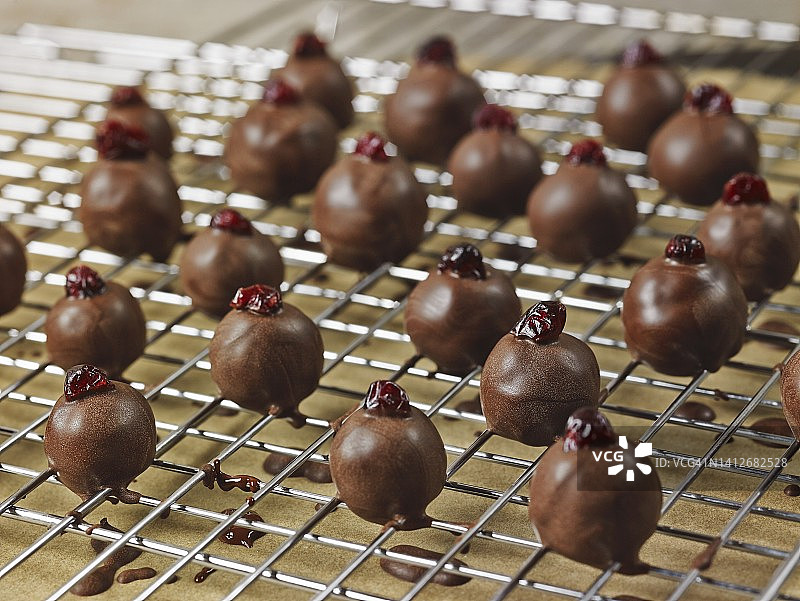 黑巧克力涂层，手卷杏仁软糖松露和蔓越莓在铁丝架上干燥图片素材