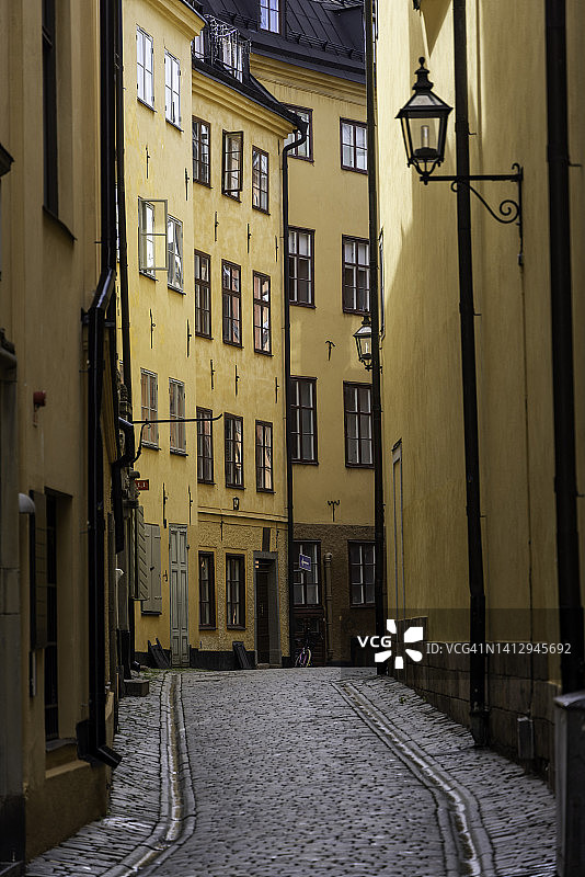 在斯德哥尔摩老城的这一典型的街道场景中，有奶油色的建筑和路灯图片素材