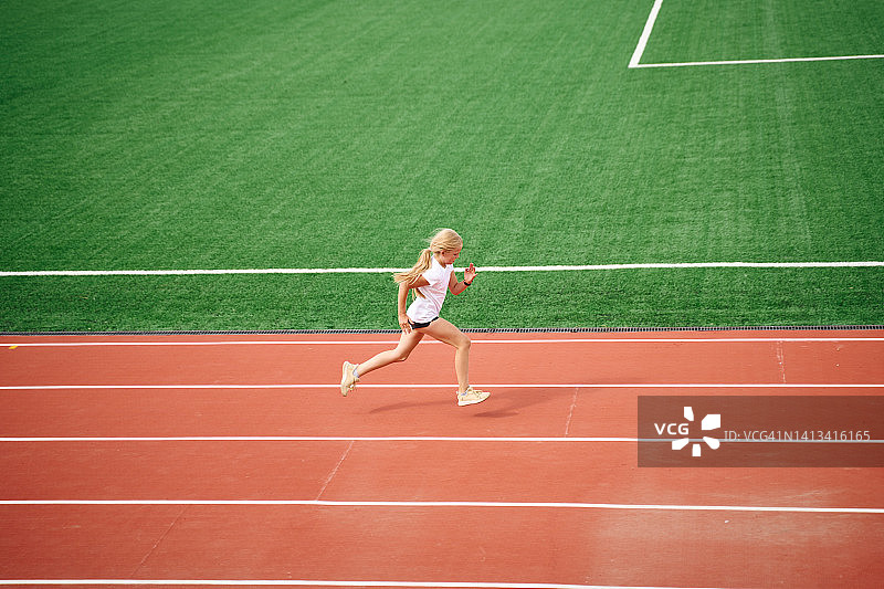 一个年轻的女孩在运动场跑步图片素材