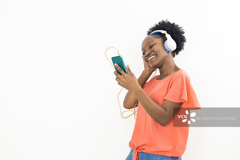 欢快的非洲裔美国年轻女性在她的智能手机上播放音乐图片素材