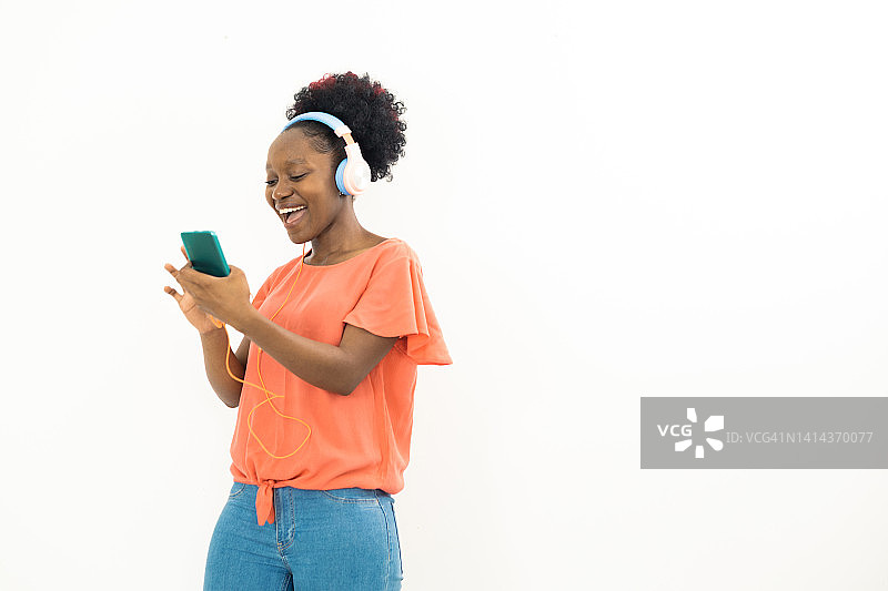 一名年轻的非洲女性用她的智能手机播放音乐的肖像图片素材