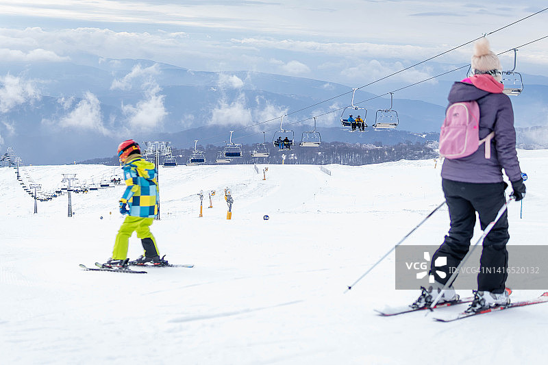 母子俩在滑雪坡上滑雪图片素材