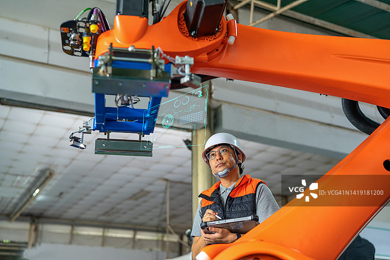 这名日本男性机器人工程师在生产线上使用数码平板检查拾取机器人的功能和运动方向。控制制造工厂的效率和质量。图片素材