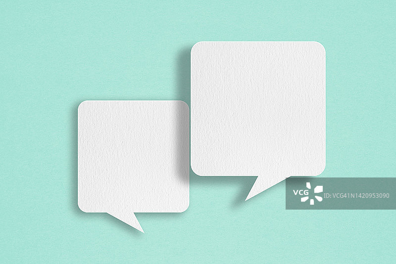 两个空白的白色语音泡沫纸剪纸，在垃圾蓝色的纸背景。关于沟通和社交媒体的概念形象图片素材