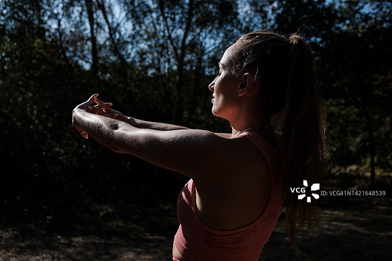 在伦敦附近的森林里健身的年轻女子的剪影。图片素材