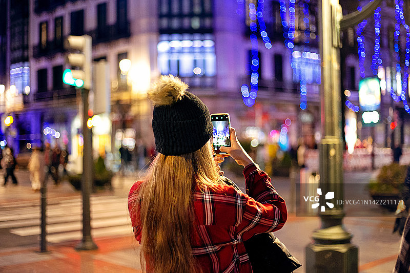 十几岁的女孩与羊毛帽子拍摄圣诞彩灯图片素材