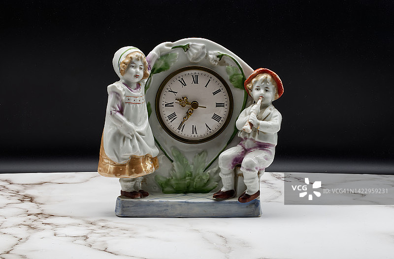 古董意大利陶瓷表时钟在大理石表和黑色背景。图片素材