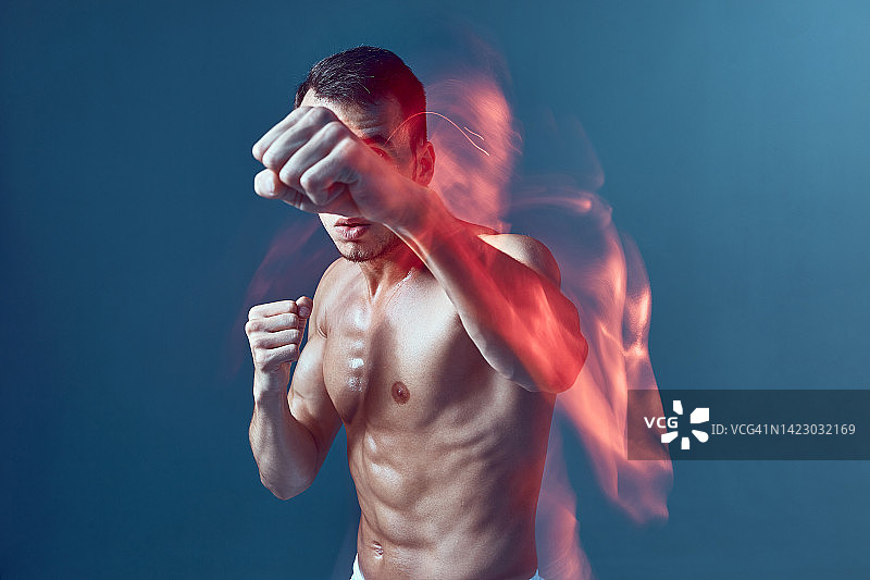 运动男性肌肉裸露躯干拳击握拳，举起手臂。长时间的曝光。战斗训练图片素材