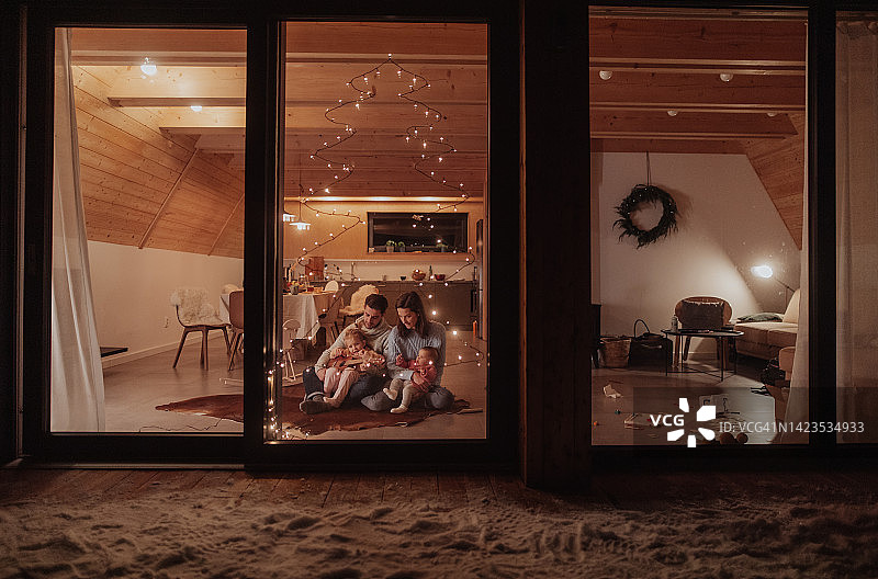 年轻快乐的一家人坐在客厅里享受圣诞节。图片素材