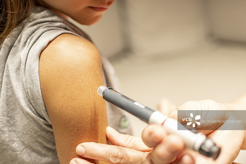 一个漂亮女孩在手臂上注射胰岛素的特写图片素材