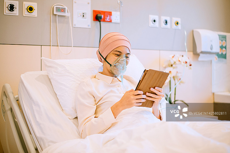 亚洲癌症患者在医院使用数码平板电脑和氧气面罩图片素材