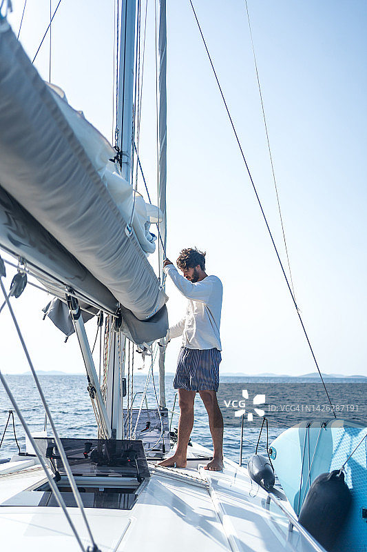 年轻人在海上用桅杆准备起航图片素材