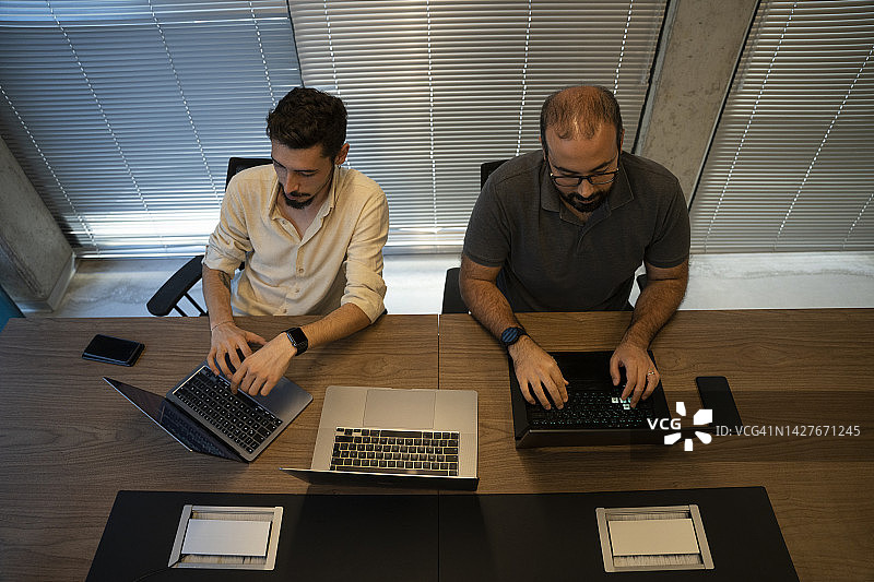 快乐的程序员画像在现代办公室与程序员在笔记本电脑上开发软件。图片素材