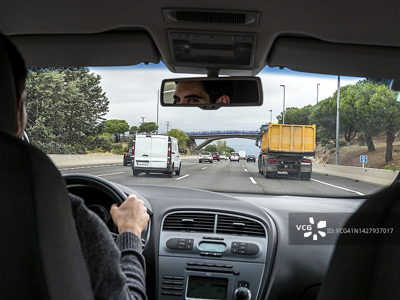从汽车的角度来看，一个年轻人在车流密集的双车道高速公路上开车图片素材