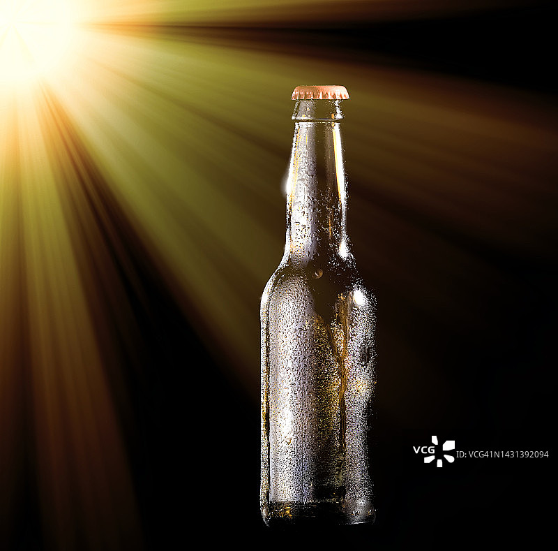 在黑色背景上被阳光照亮的啤酒瓶。图片素材