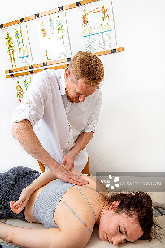 整骨医生正在治疗一名年轻女子的背部图片素材