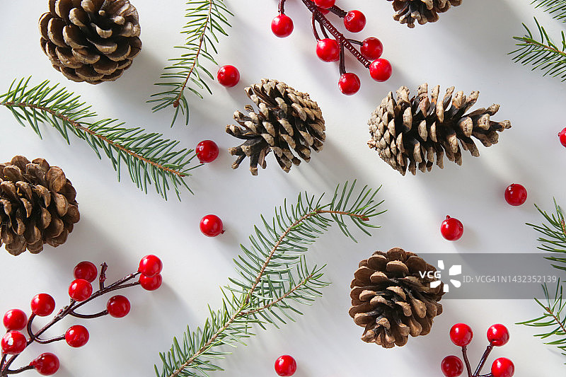 圣诞树的树枝，针叶树球果和红色浆果，节日饼干和装饰品，俯视图在白色背景。圣诞节，寒假，新年的概念。图片素材