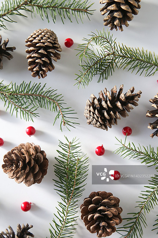 圣诞树的树枝，针叶树球果和红色浆果，节日饼干和装饰品，俯视图在白色背景。圣诞节，寒假，新年的概念。图片素材