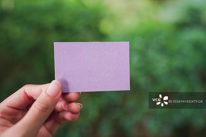女人的手拿着一张空白的紫色小纸，用来添加文字。图片素材