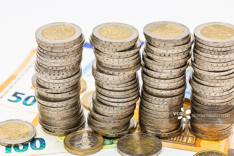 欧元纸币上的一堆欧元硬币。商业、财富、金融和储蓄的概念图片素材