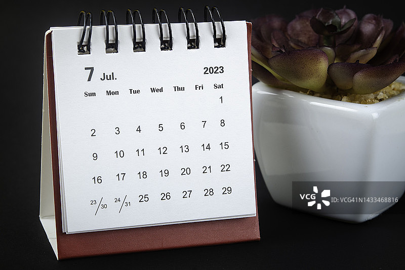 2023日历台:7月是组织者计划的一个月，在黑色纸背景的室内植物截止日期。图片素材