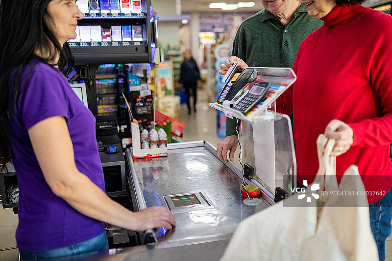 成熟女性用智能手机在超市购物图片素材